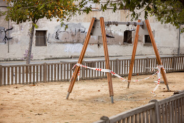 Deserted playground in a residential area due to Covid-19. Baby swings that roll up to not be used. Consequences of the coronavirus outbreak: quarantine, confinement, no social life, restrictions.