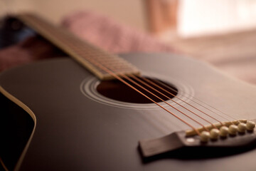 Fototapeta premium Black acoustic guitar on a bed a sunny day in a beautiful room