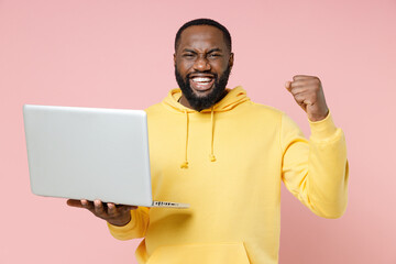 Happy young african american man 20s wearing casual yellow streetwear hoodie standing working on...