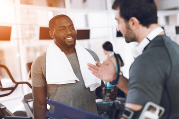 Two men communicate at racetracks in modern gym.