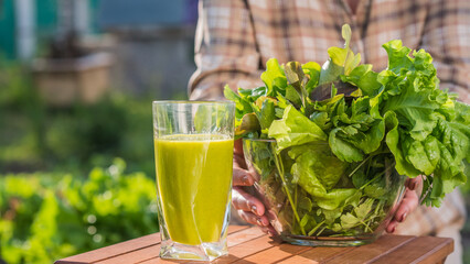A woman holds a glass of green smoothie and a plate of lettuce. Healthy eating and diet