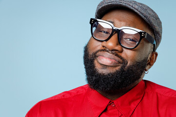 Close up of smiling confused young bearded african american man 20s wearing casual red shirt cap...