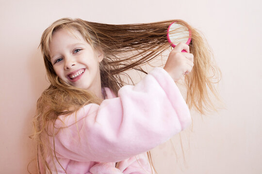 little girl combs her hair after a shower