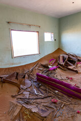 Demolished house interior buried in sand, with broken furniture, in ghost village Al Madam in...