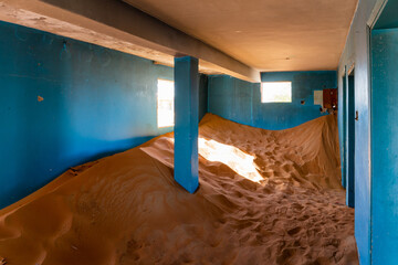 Neglected house interior with blue walls buried in the sand in Al Madam ghost village in United...