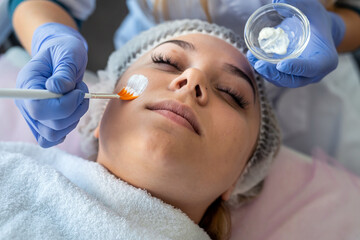 beautician applying healing cream on a young female face client