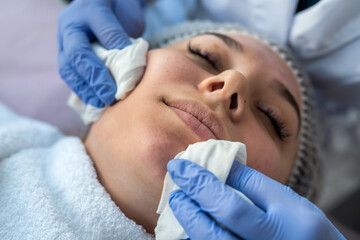 Fototapeta na wymiar Cosmetologist preparing face to the procedure of young woman lying on a table in a beauty clinic