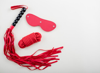 BDSM set on a white background. Leather red eye mask rope and whip. Copy space