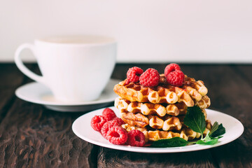 yummy belgian waffles with raspberries and mint leaves on wooden table