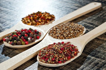 A mixture of various spices in a wooden spoon. Spices and seasonings on an old shabby board. Mix on a pile close up.