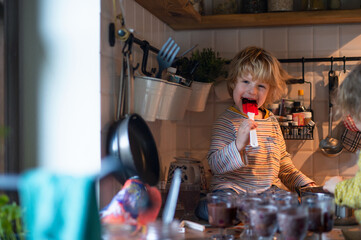 Small boy indoors in kitchen at home, helping with cooking.