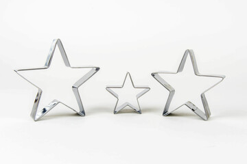 Three metal cookie cutters in the shape of a star of different sizes on a white background. Family concept - mom, dad and child.