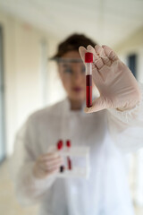 young pretty nurse looking at a blood sample for diagnostic on Coronavirus