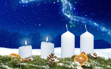 two candles on an advent wreath burns with wintery background