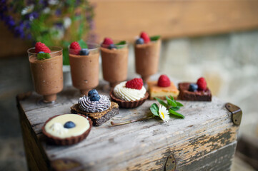 Selection of colorful and delicious cake desserts on rusty wooden box.