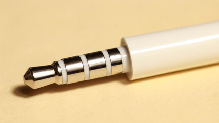 White plug from headphones close-up on a beige background.