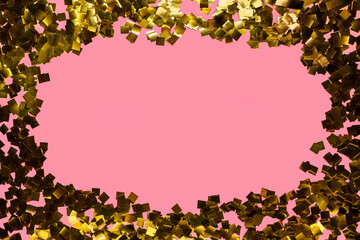 Golden glitter confetti on pink background. Festive holiday background. Top view, flat lay. Blank space for text or image.