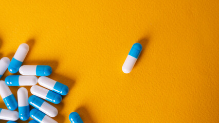 white and blue pills on yellow background