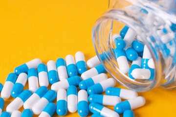 white and blue pills on yellow background