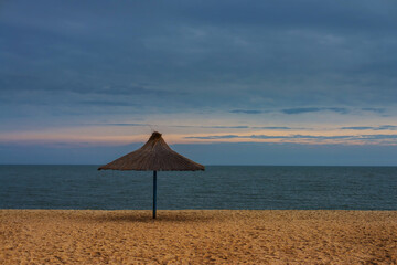Reed umbrella on the shore of the sea against the rising sun