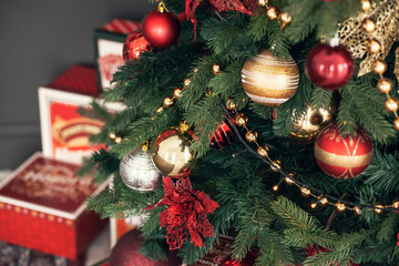 Gold and red Christmas toys, balls, garlands on a spruce branch on dark red background