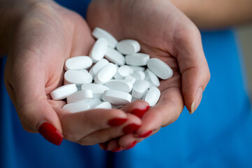 doctor in blue uniform holding many white pills in his hands