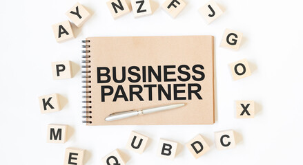 Text BUSINESS PARTNER on the craft colored notepad with block wood cubes on the white background
