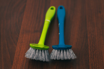 Green and blue dishwashing brushes isolated on a wooden background. Close-up
