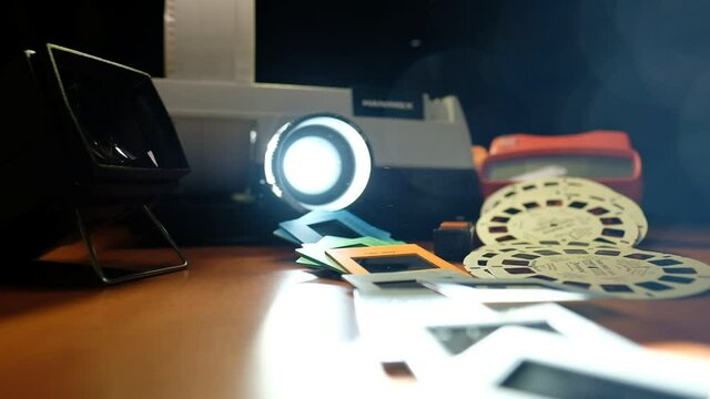 Vintage products and old "gadgets" video session, a slide projector and other vintage stuff beautifully laid and lit. As the projector throws a strong light,- dust particles are noticeable.