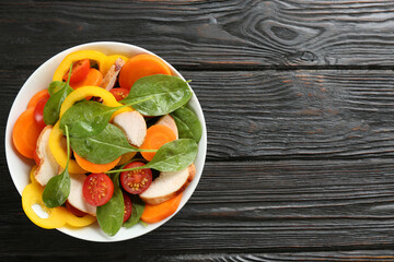 Delicious fresh chicken salad served on black wooden table, top view. Space for text