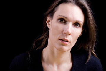 Dark studio portrait of a serious brunette. Studio portrait isolated on black background.