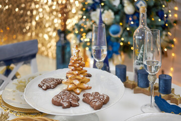 New Year. Christmas table is served with food, champagne, candles, blurred background of a Christmas tree. 2021