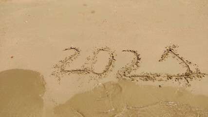 Numbers 2021 year written on the sand in sea beach