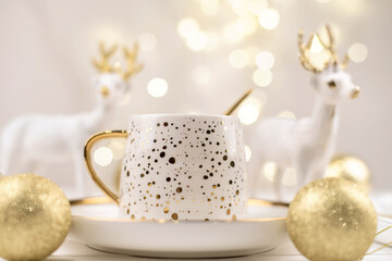 Beautiful composition with new year's deer and a white Cup with a Golden new year's drink.