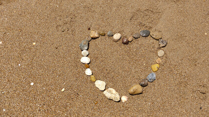 symbol of the heart drawing stones on the sand