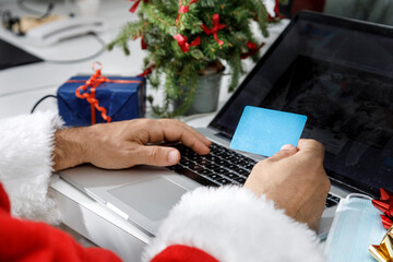 dettaglio della mano di babbo natale che tiene in mano una carta di credito pronto a fare un ordine...