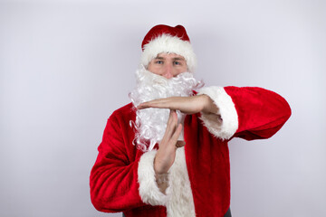 Man dressed as Santa Claus standing over isolated white background Doing time out gesture with hands, frustrated and serious face