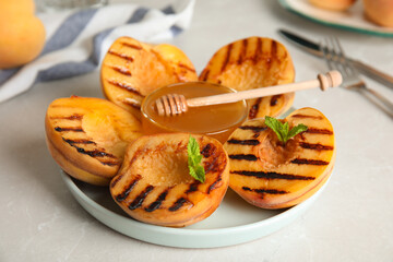 Delicious grilled peaches with honey and mint on grey  table