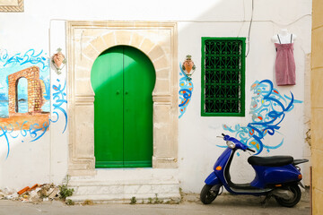 Fototapeta na wymiar scooter in front of a church white house in oia island Tunisia