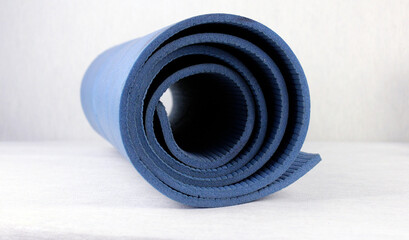 Blue folded yoga mat on light background