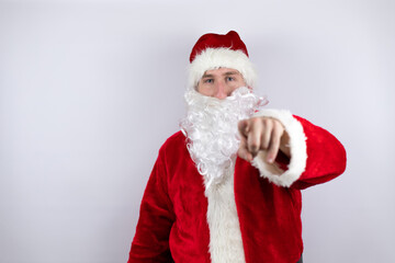 Man dressed as Santa Claus standing over isolated white background pointing to the front with finger