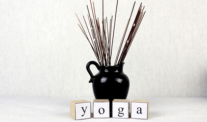 Wooden cubes with the inscription "yoga" with a small jug with decorative incense sticks