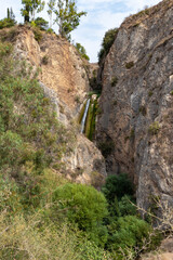 Fototapeta na wymiar HaTanur waterfall flows from a crevice in the mountain and is located in the continuation of the rapid, shallow, cold mountain Ayun river in the Galilee in northern Israel