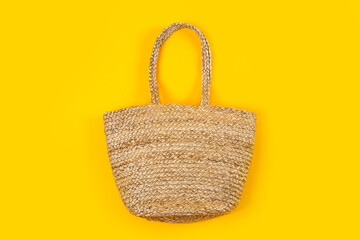 Stylish woman's straw bag on yellow background, top view