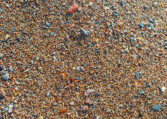 Wet colored pebbles on a beach in the surf