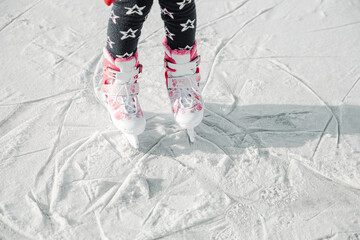 Figure skates on girl legs on ice covered with snow and with traces made by skating. Child winter...