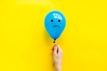 Sadness emotion face on balloon - depression mood background. Top view, copy space