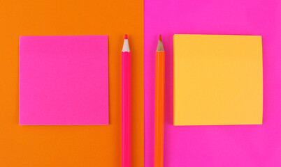 Bright orange and pink background with sheets of paper for writing and pencils