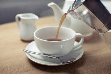 Pouring hot coffee in the white cup