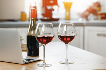 Two wine glasses with red wine on wooden kitchen counter